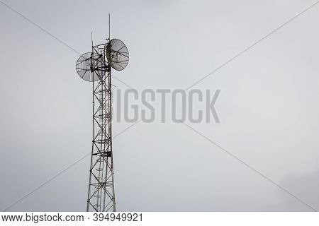 Communication Tower With The Overcast Sky Background.