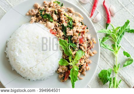 Rice Topped With Stir-fried Pork And Basil In Dish On Tablecloth.