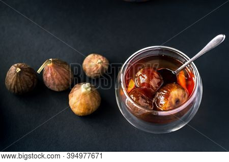 Fruit Jam Of Figs In Glassware Stands On A Black Background And Next To Lie The Fruits Of Figs