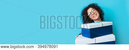 Caucasian Curly Haired Lady Is Smiling At Camera With Glasses While Holding Some Present Boxes On A 