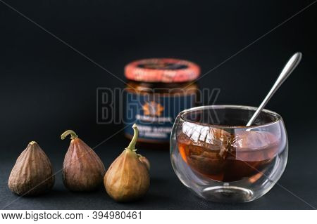 Fruit Jam Of Figs In Glassware Stands On A Black Background And Next To Lie The Fruits Of Figs