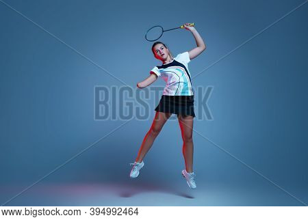 In Jump. Beautiful Handicap Woman Practicing In Badminton Isolated On Blue Background In Neon Light.