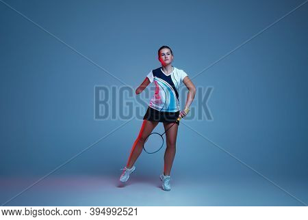 In Jump. Beautiful Handicap Woman Practicing In Badminton Isolated On Blue Background In Neon Light.