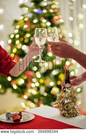 Cropped Image Of Young Couple Toasting With Champagne Flutes When Celebrating Christmas At Home