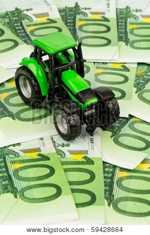 a tractor standing on euro banknotes. symbolic photo for costs, revenues and subsidies a farmer in agriculture