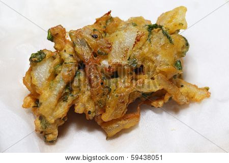 An onion bhaji, straight from the pan, draining on a sheet of kitchen paper