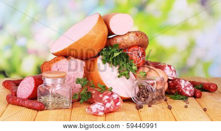 Lot of different sausages on wooden table on natural background