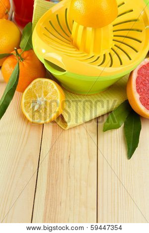 Citrus press and fruits on wooden background
