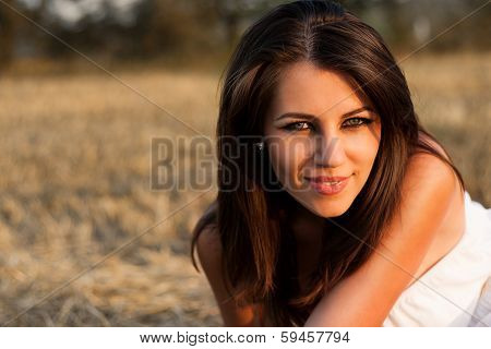 Beautiful girl with sunflower in the hay.