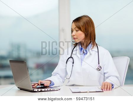 medicine and healthcare concept - busy doctor with laptop computer