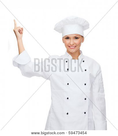 cooking, advertisement and food concept - smiling female chef, cook or baker pointing finger up to something