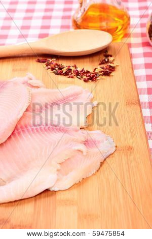 Raw fish tilapia on cutting board and spices