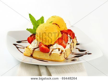 Belgian waffle topped with whipped cream, fresh strawberries and ice-cream