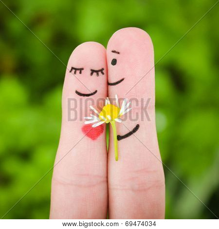 Happy couple. Man is giving flowers to a woman.