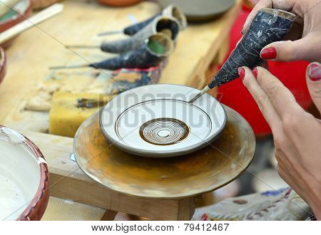 BRASOV, ROMANIA - AUGUST 27, 2014: Woman painting traditional plates at a fair with specific design