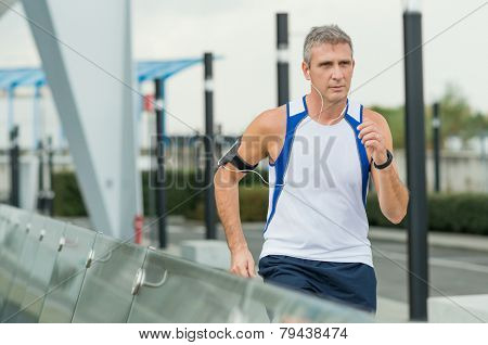 Mature Man Running And Listening To Music On Earphones In the City
