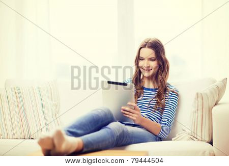 home, technology and internet concept - smiling teenge girl lying on the couch with tablet pc computer at home