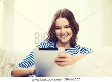 home, technology and internet concept - smiling teenge girl lying on the couch with tablet pc computer at home