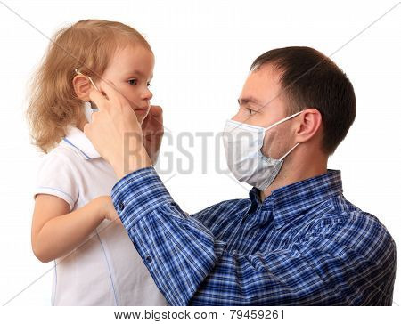 Dad puts a medical mask on to daughter.