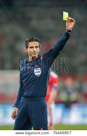 KLAGENFURT, AUSTRIA - MARCH 05, 2014: Referee Deniz Aytekin (Germany) show a yellow card in a friendly soccer game between Austria and Uruguay.