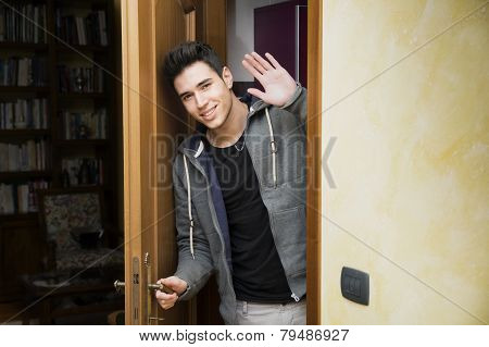 Smiling young man in doorway waving at the camera