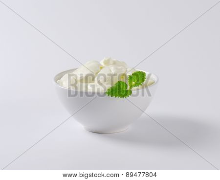 portion of fresh white joghurt in the bowl, decorated with piece of mint