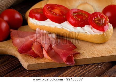 Slice Of Prosciutto Ham On Chopping Board With Fresh Baguette