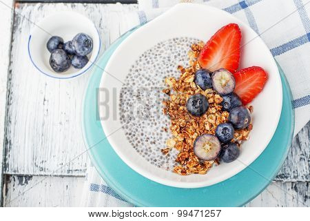 Chia seed pudding made with blueberries,  strawberries and mint on a wooden background. Selective fo