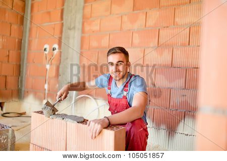 Smiling Worker Building Brick Walls With Cement, Mortar And Putty Knife. Mason Using Mortar For Buil