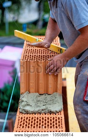 anonymous construction worker on a construction site during construction erected a wall of bricks. brick wall of a solid house. symbol picture for illegal work and botch