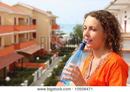 Frau stehend auf Balkon und hält die Flasche und trinken daraus