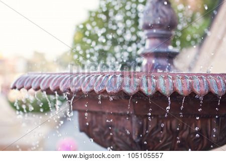 Close-up of an old stone fountain with dripping water on blurred background