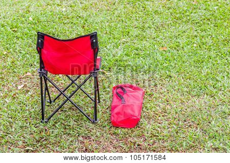 The Red Folding Chair And The Cover On Green Grass.