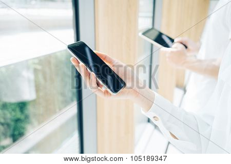 Young man and young woman holding in hands their gadgets. Blurred background on the background.