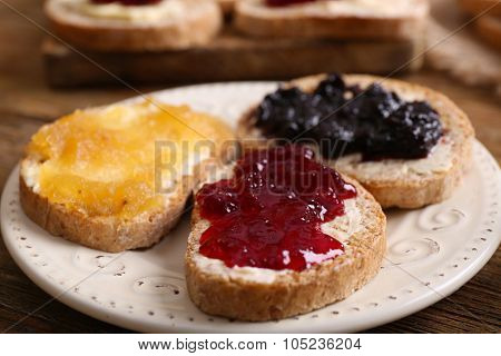 Fresh toast with butter and different jams on table close up