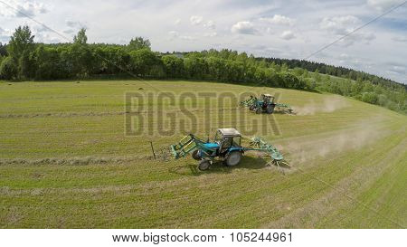 Two tractors work on field near forest at summer sunny day. Aerial view videoframe