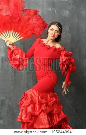 Beautiful dancer in a red dress with a big red fan of feathers in hand