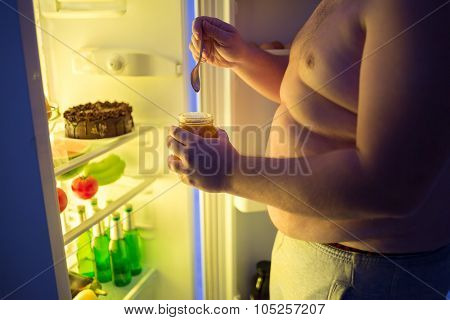 Close up of fat man break diet and takes at night dangerous unhealthy sweet from fridge
