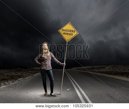 Young woman satnding on road with signboard