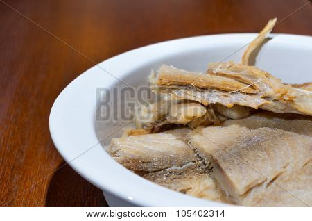 Pieces of dry fish lying on white plate drained in water, preparation fanesca concept