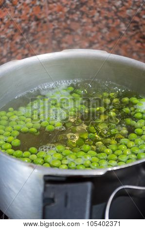 Green peas cooking in silver colored metal pot. fanesca preparation concept