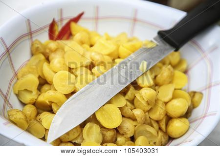 Bowl of ollucos cut in halfs with knife lying on top, preparing fanesca concept
