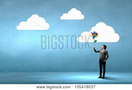 Young happy guy in casual with colorful windmill in hand