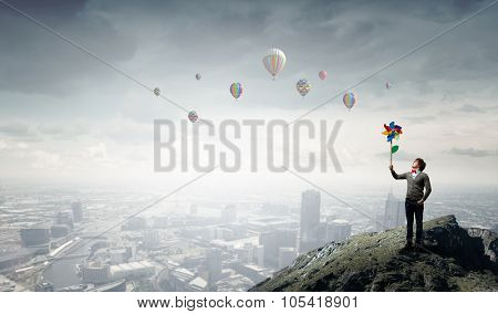 Young happy guy in casual with colorful windmill in hand