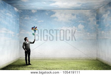 Young happy guy in casual with colorful windmill in hand