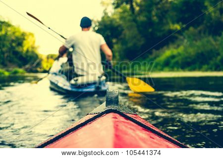 nose of canoe floating behind rower on a river