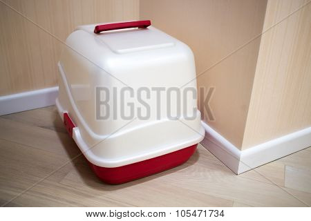 White and red litterbox standing in corner of corridor.