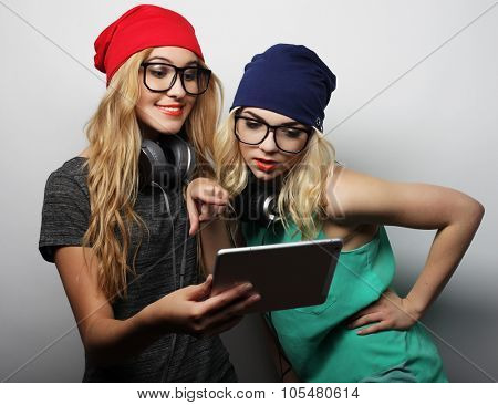 two hipster girls friends use digital tablet, studio shot over gray vackground