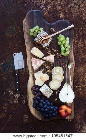 Wine appetizers set: French cheese selection, honeycomb, grapes, peach and walnuts on rustic wooden