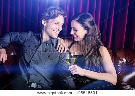Young flirty couple with wine at a club lounge